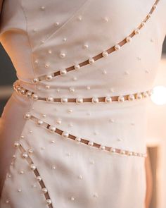 a woman in a white dress with pearls on it