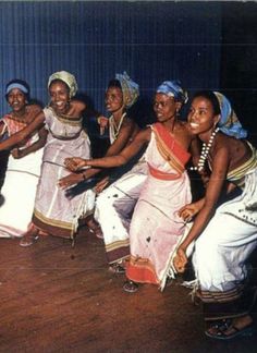 a group of women are dancing together on the dance floor in traditional garb and headdress