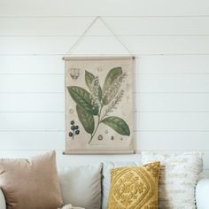 a living room with white walls and green leaves on the wall hanging above the couch