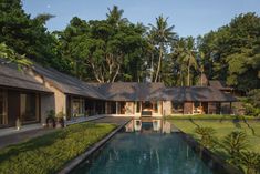 a house with a pool in front of it surrounded by trees and grass on both sides