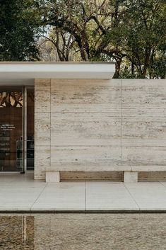 a bench sitting in front of a building next to a body of water with trees behind it