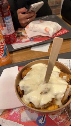 a bowl filled with food sitting on top of a table next to a bottle of soda