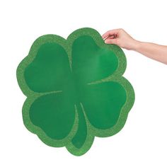 a hand holding a green clover shaped paper plate