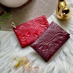 two red leather cases sitting on top of a white fur covered floor next to a gold vase