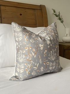 a white bed topped with pillows next to a wooden headboard