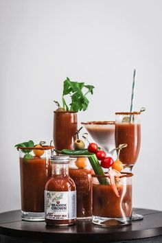 three glasses filled with different types of sauces and garnishes on a table