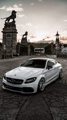 a white car parked in front of a statue