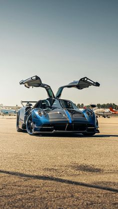 a blue sports car parked on top of an airport tarmac