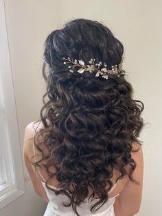 the back of a woman's head with long curly hair and a tiara