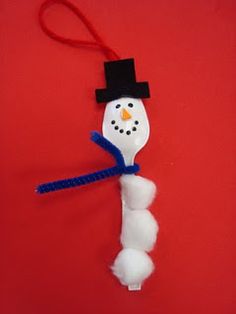 a snowman ornament hanging on a red background with a blue ribbon and black hat