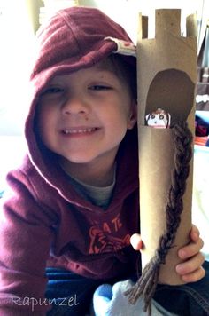 a young boy is holding up a cardboard castle