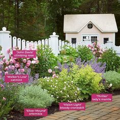 a garden with various types of flowers in front of a white picket fence and house