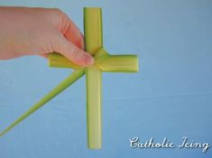 a hand is holding a piece of paper that has been folded into the shape of a cross