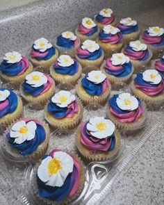 there are many cupcakes with flowers on them in the plastic tray, ready to be eaten