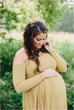 a pregnant woman in a tan dress is posing for the camera with her hands on her hip