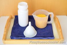 a tray with two measuring cups and one measuring spoon on top of a blue towel