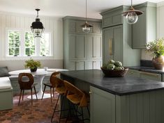 a kitchen with green cabinets and an island in front of the countertop, surrounded by stools