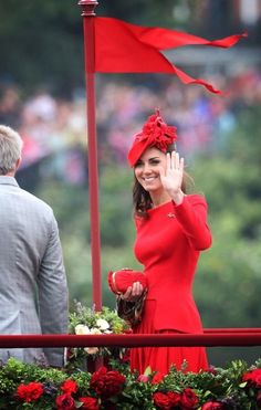 a woman in a red dress waves to the crowd