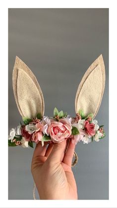 a hand holding a flower and bunny ears headband