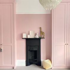 a living room with pink walls and white trim on the fireplace mantel in front of it