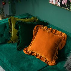 three different colored pillows on a green couch