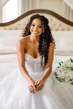 a woman in a wedding dress sitting on a bed