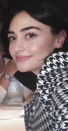 a woman sitting at a table next to a man in a black and white shirt