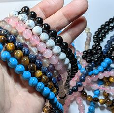 a person holding several bracelets with different colors and designs on them in their hands