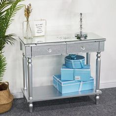 a silver table with blue boxes on it and a potted plant in the corner