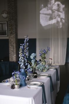 the table is set with blue flowers and plates