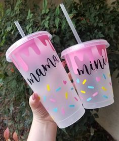 two plastic cups with pink frosting and sprinkles that say mama mia