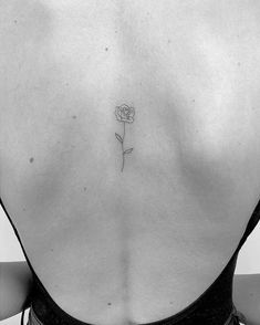 a woman's back with a single rose tattoo on her left side ribcage