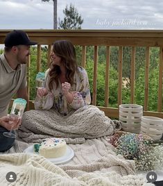 a man and woman are sitting on a deck with a cake in front of them