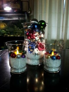 three glass vases filled with ornaments on top of a table