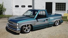 a blue pick up truck parked in front of a white building