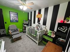 a baby's room with black and white stripes on the walls, green accents