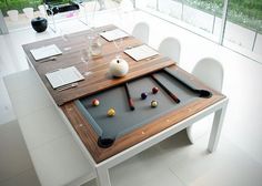 a pool table in the middle of a room with white chairs and tables around it