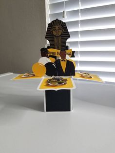 an image of a table with food on it and a paper cut out of the egyptian god