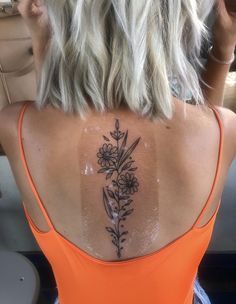 the back of a woman's neck with flowers tattooed on her upper arm and shoulder