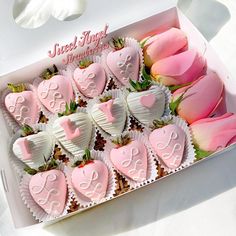 a box filled with lots of pink and white heart shaped chocolates next to flowers