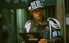 a man in uniform holding a clipboard and looking at something on his hand while standing next to a building