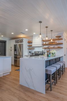 a kitchen with an island and several stools in front of the countertop area