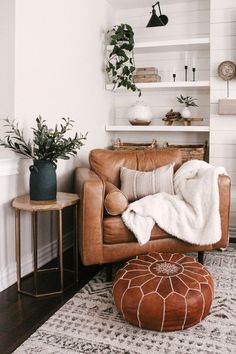 a living room with a brown leather chair, ottoman and potted plants on shelves