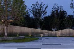 an empty parking lot at night with lights on the trees and fenced in area