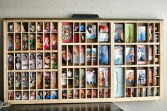 a wooden box filled with lots of pictures on top of a table next to a wall