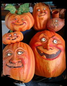 pumpkins with faces painted on them sitting in a pile