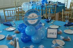 a table with blue and white plates, silverware, and balloons in the shape of an airplane