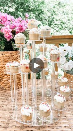 cupcakes are arranged in clear vases on a table with pink and white flowers