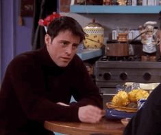 two men sitting at a table with food in front of them on the set of friends