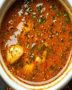 a close up of a bowl of soup with bread on the side and garnished with parsley